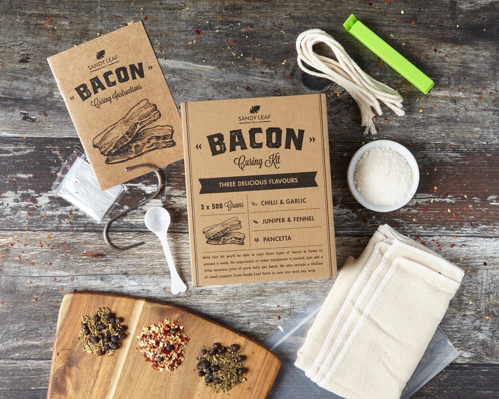 Bacon curing kit with dry cure, three seasoning sachets and sliced home-cured streaky bacon on a board