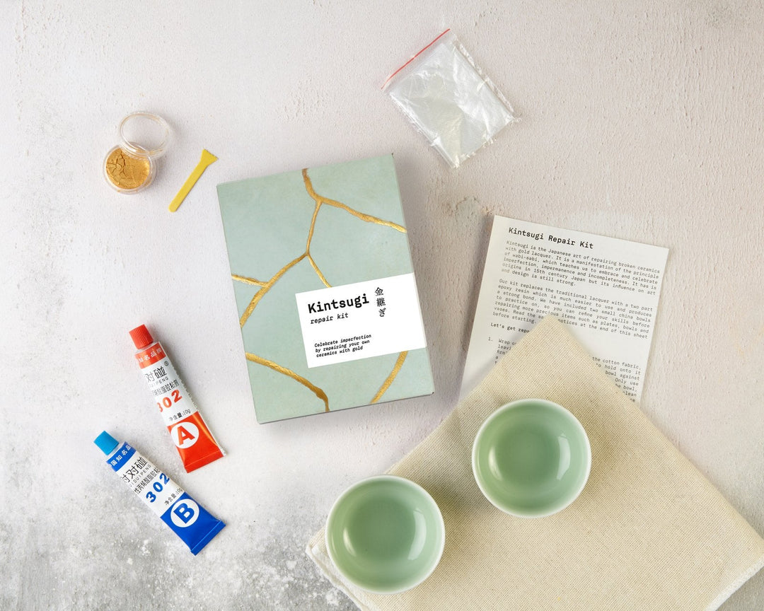 Kintsugi repair kit laid out for an adult craft evening with practice bowls, gold pigment and epoxy