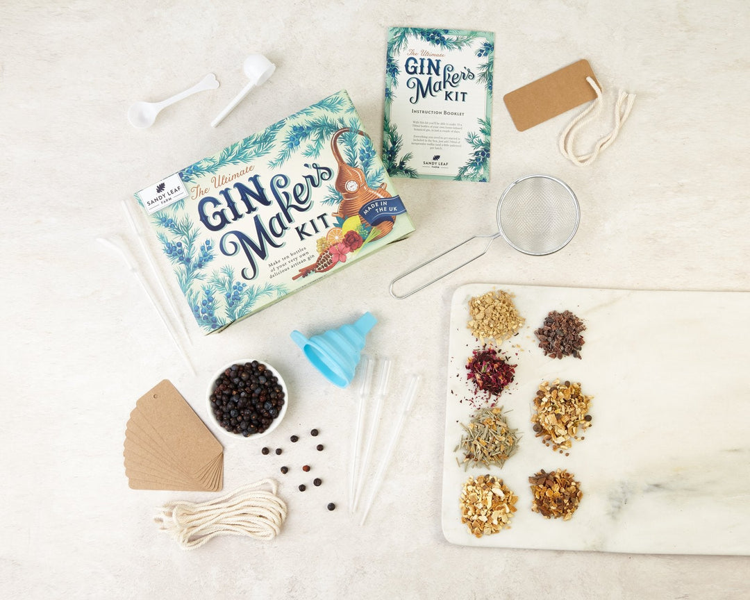 Gin botanicals including juniper berries and citrus peel laid out beside a make your own gin kit